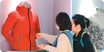 图为两名参展商在福建省泉州市晋江国际会展中心的安踏展位上了解“安踏风暴甲”防暴雨级冲锋衣。新华社记者 魏培全摄