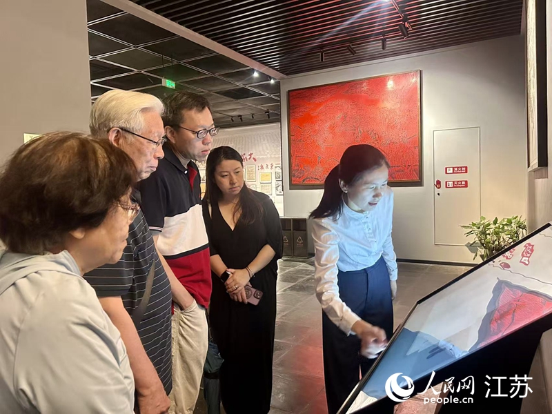 沙家浜革命历史纪念馆工作人员向游客介绍一体机上的行军鞋。人民网 王丹丹摄