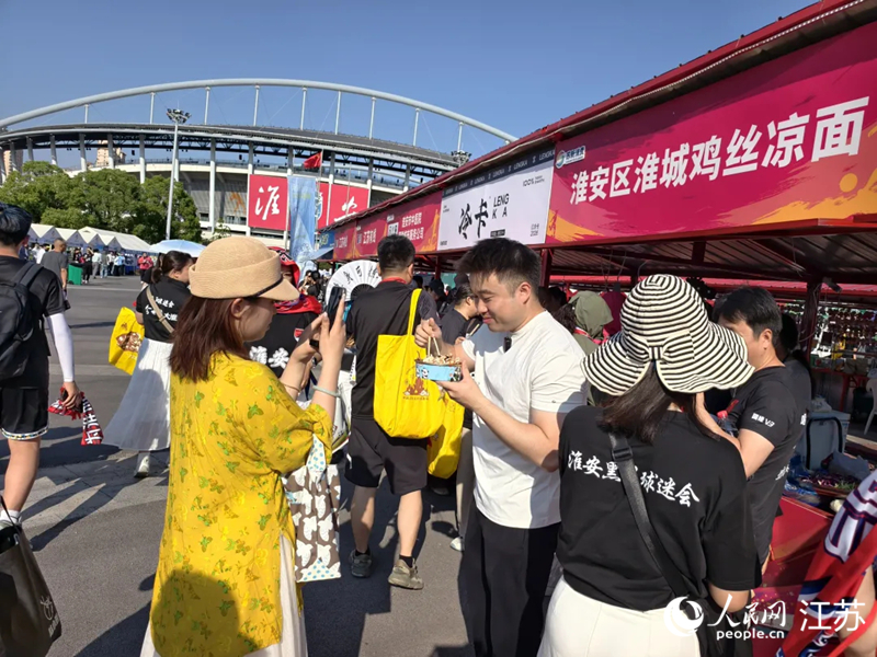 “苏超”赛场旁，不少游客品尝淮安美食。人民网 江楠摄